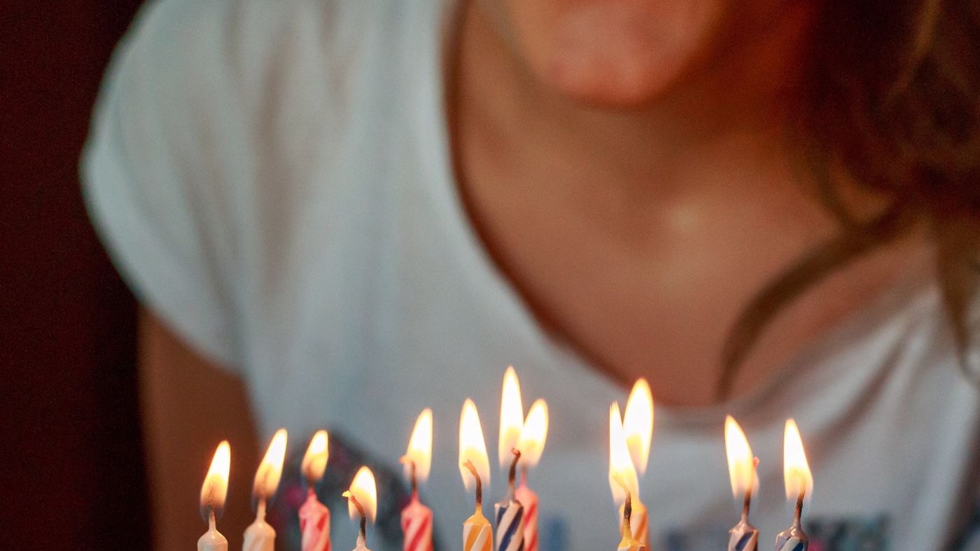 Mulher assoprando velas de aniversário.