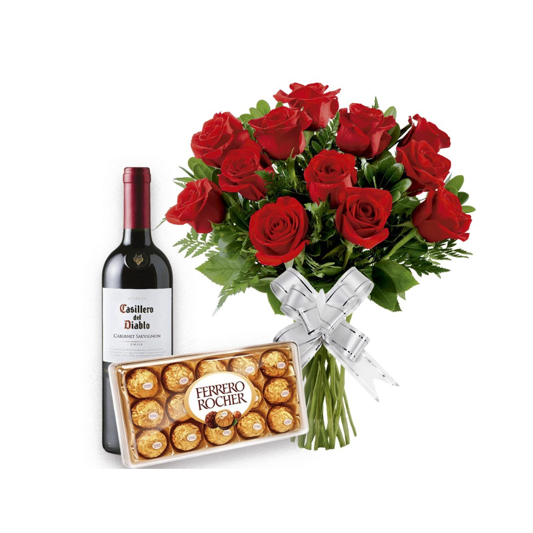 Uma caixa de chocolates ao lado de um vinho e buquê de flores.