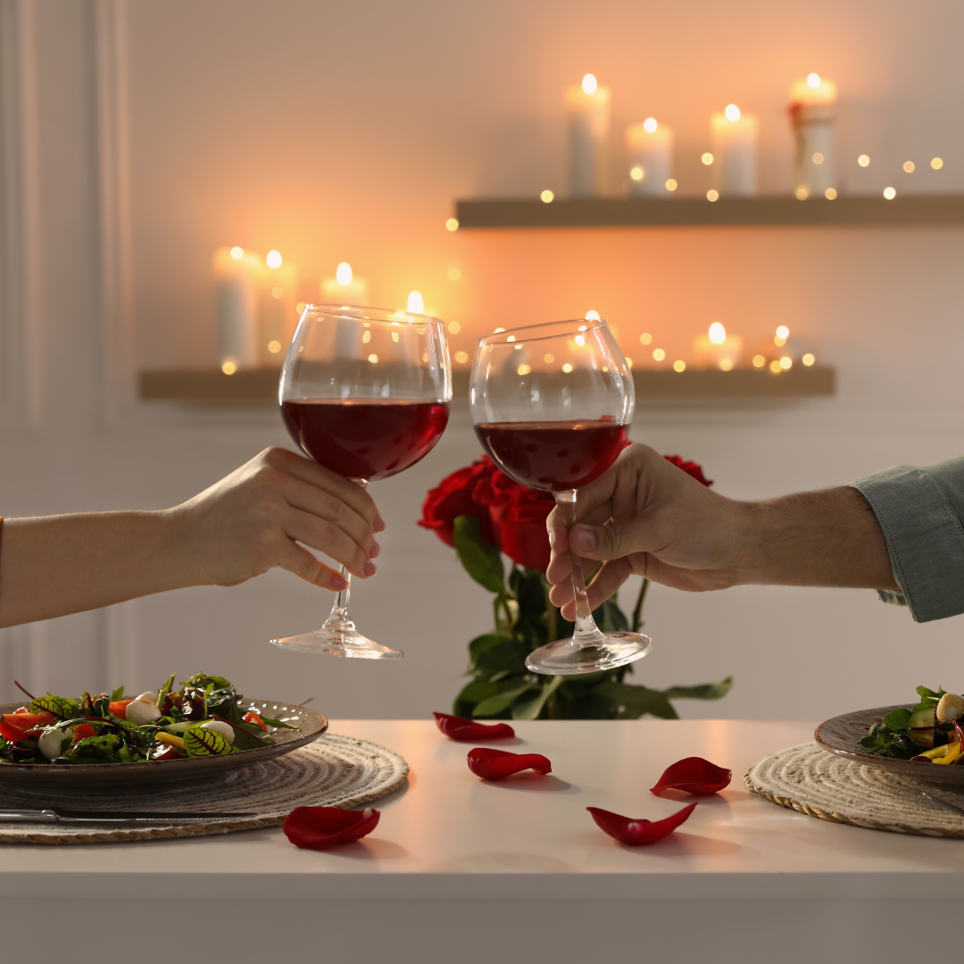 Jantar a luz de velas e ao centro, duas pessoas brindando com vinho