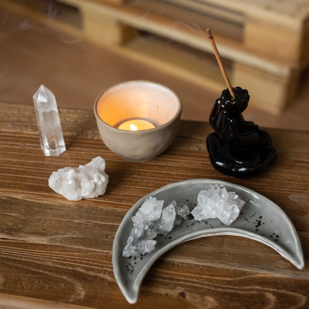 Vela, cristais e incensos em cima de uma mesa de madeira.