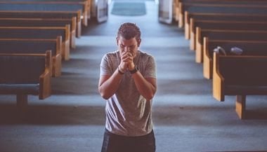 Homem rezando no altar de uma igreja