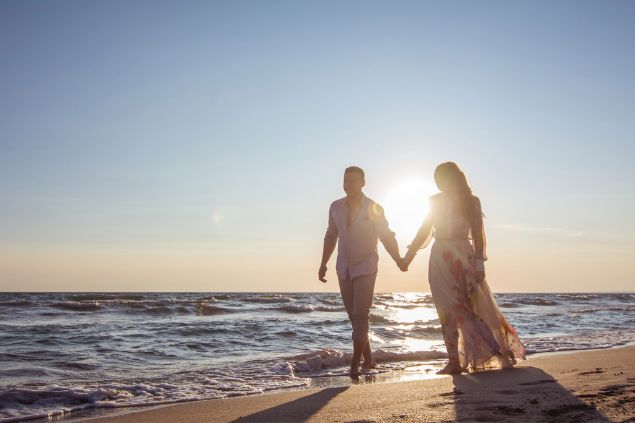Casal andando de mãos dadas na praia