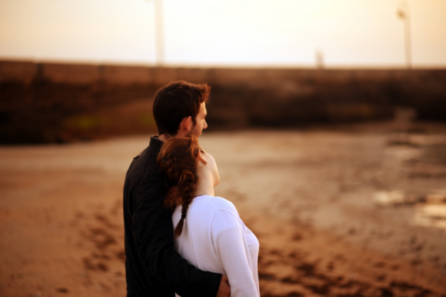 Casal abraçado enquanto olha o horizonte