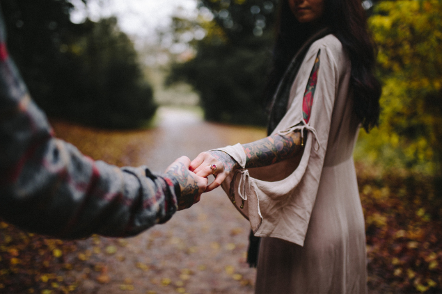 Casal de mãos dadas em um bosque com uma caminhada cimentada