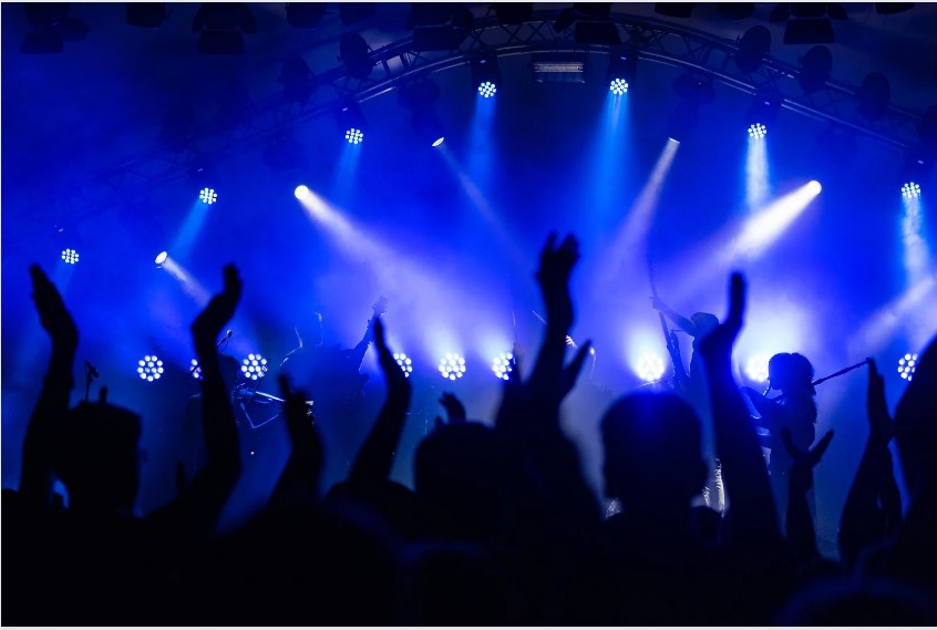 Foto de uma balada, com luzes neon e mãos levantadas