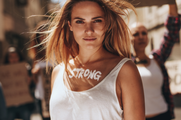 Mulher com a palavra 'strong' pintada na região abaixo do pescoço
