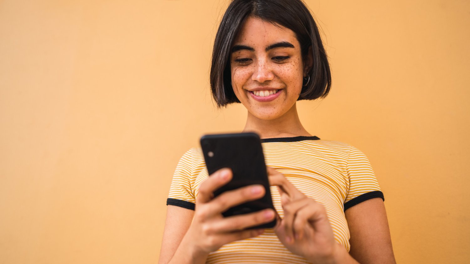 Mulher sorrindo ao olhar o celular