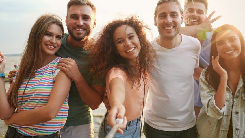 Homens e mulheres sorrindo para foto.