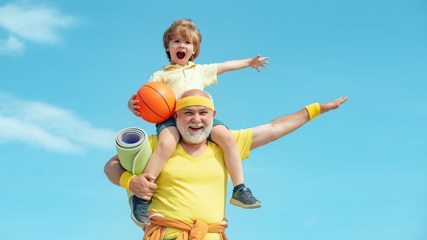 Avô carregando neto, com bola de basquete na mão