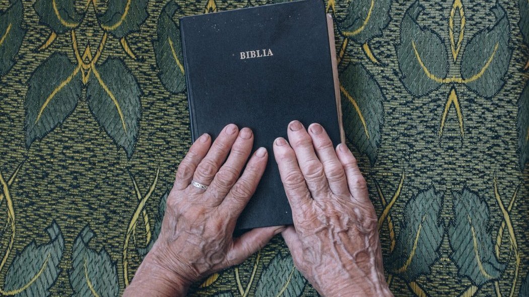 Unsplash/Raul Petri Idoso com mão sobre Bíblia