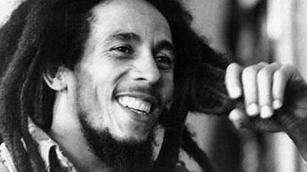 Bob Marley sorrindo com a mão em seus cabelos.