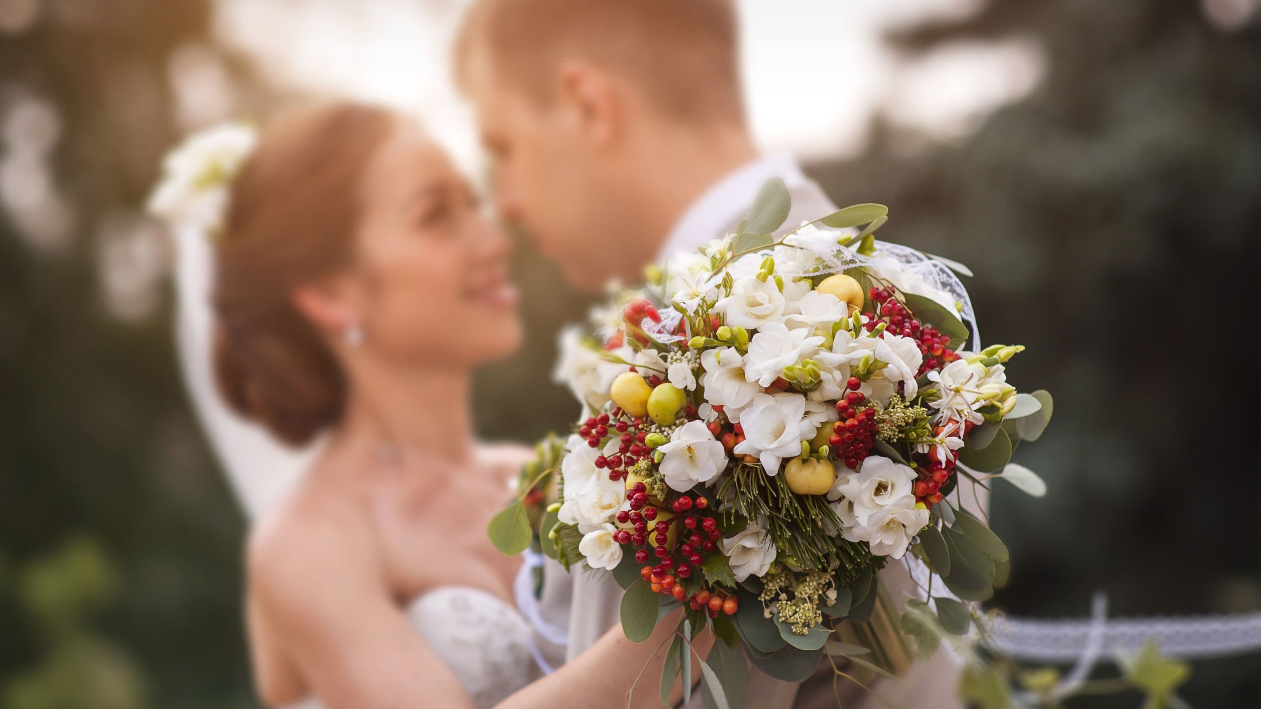 Noiva segurando um buquê de flores enquanto abraça o noivo