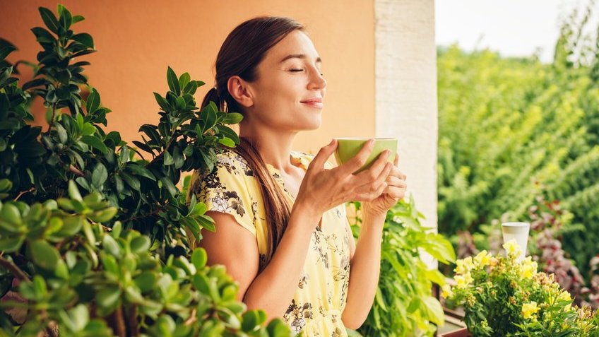 annanahabed / 123rf Mulher branca segurando caneca verde e olhos fechados.