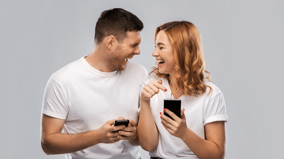 Syda Productions / Canva Casal rindo enquanto olha o celular