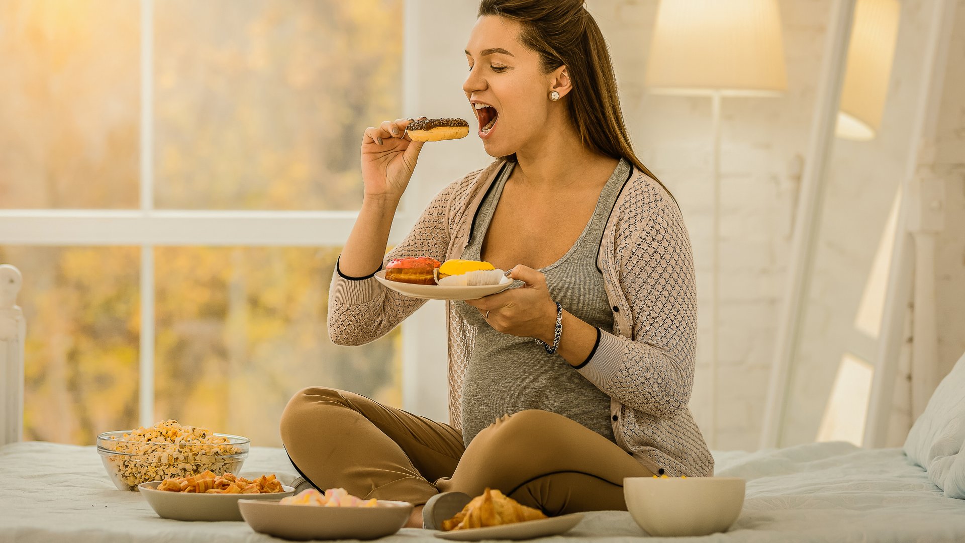 Mulher grávida comendo bastante comida na cama