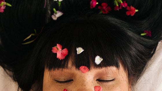 Mulher de olhos fechados com petadas de flor em seu rosto