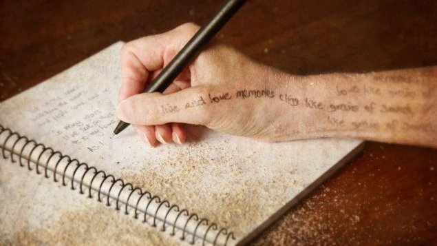 Mão segurando caneta e escrevendo em um livro