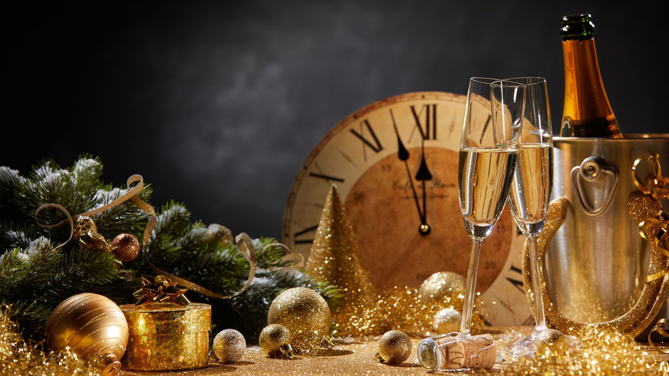 Taças de champanhe ao lado de um relógio e enfeites de ano novo