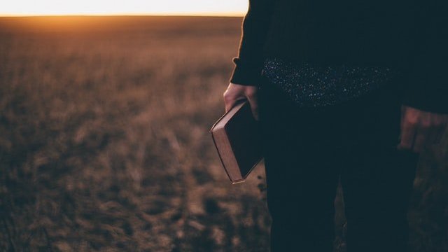 Uma pessoa sem aparecer o rosto segurando uma bíblia na mão