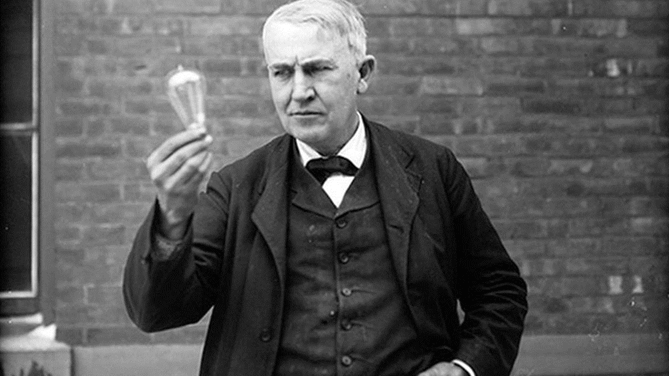 Thomas Edison segurando uma lâmpada.