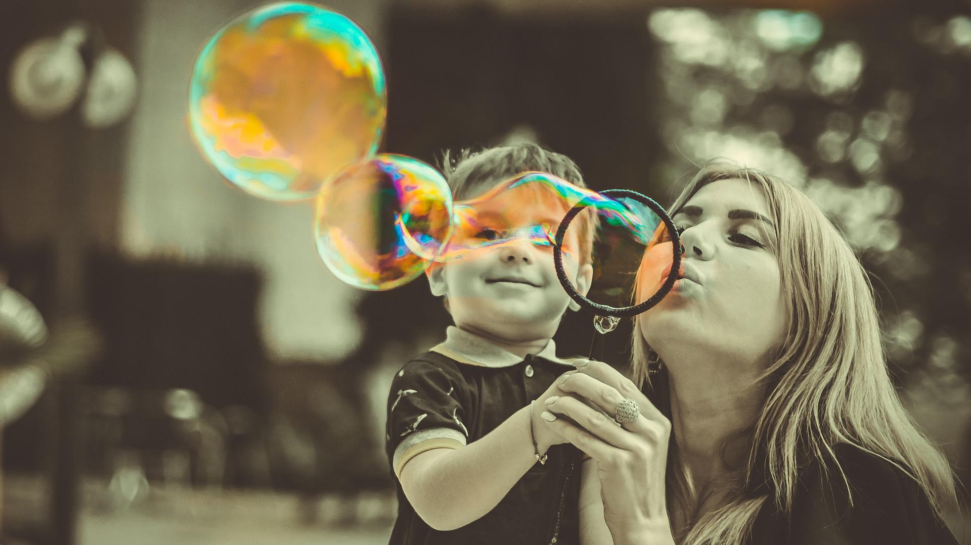 Mãe e filho assoprando bolinhas de sabão em um parque.