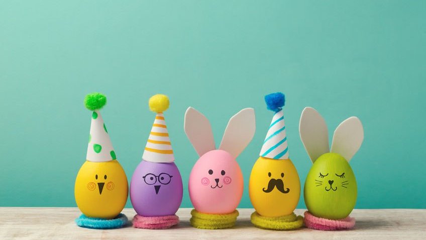 Ovos de galinha coloridos com desenhos de rostos, chapéus e orelhas de coelho