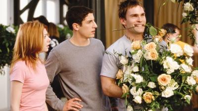 Divulgação/Universal Pictures Michelle e Jim olhando para Stifler que segura um buquê de flores nos braços, e uma rosa entre seus dentes.