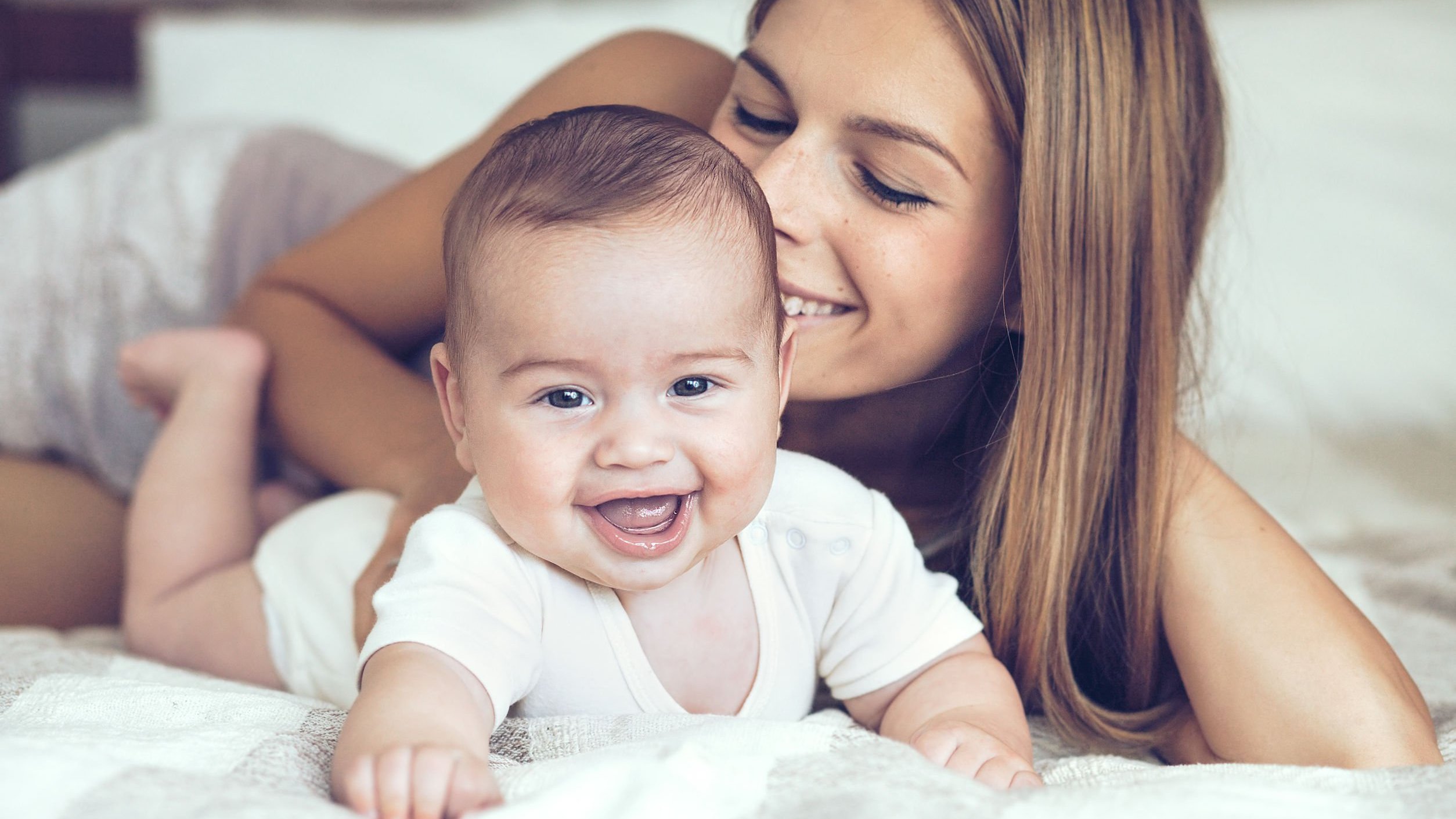 Mãe e filho deitados na cama sorrindo