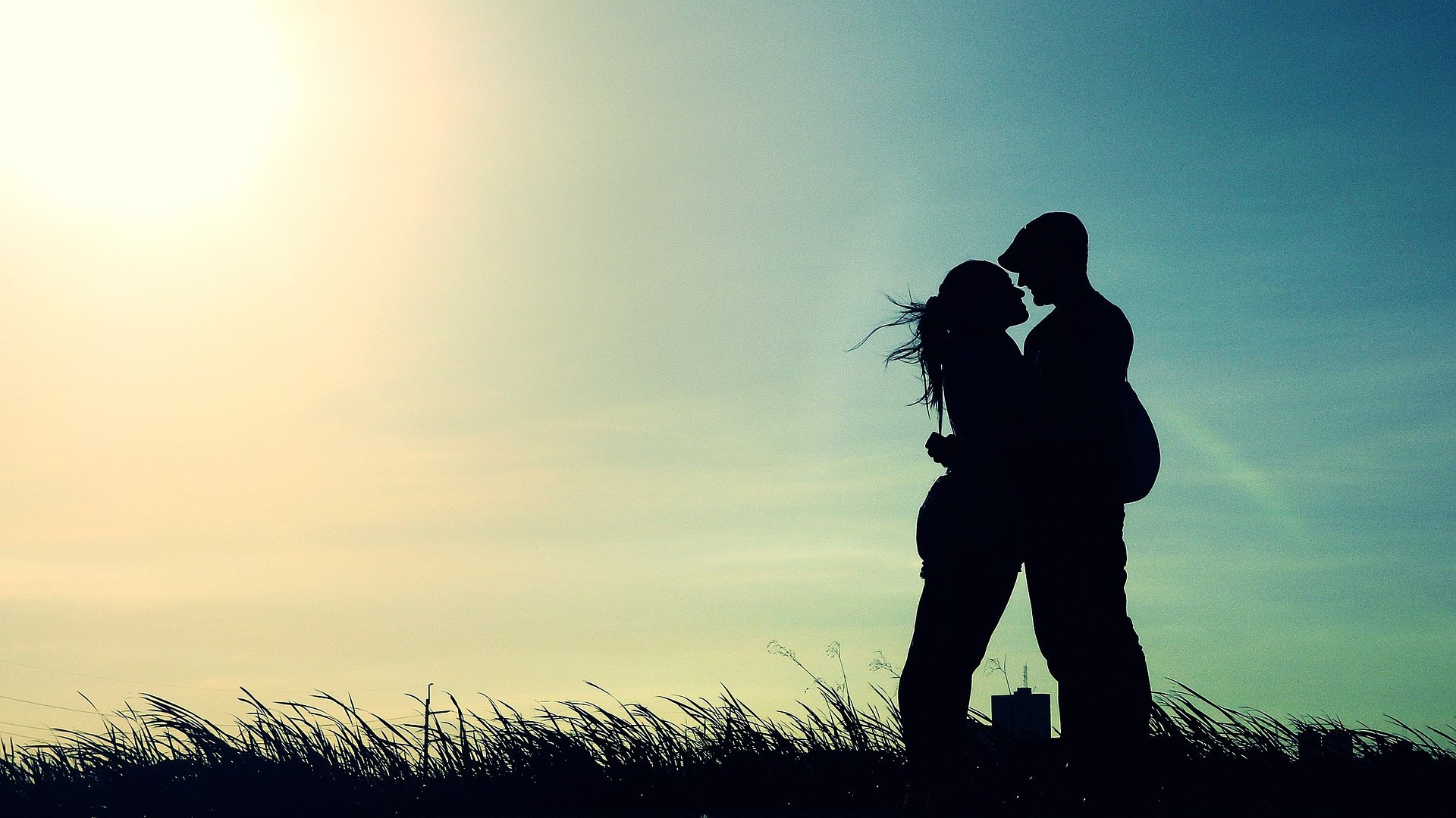 Silhueta de casal se beijando com o sol brilhando atrás.