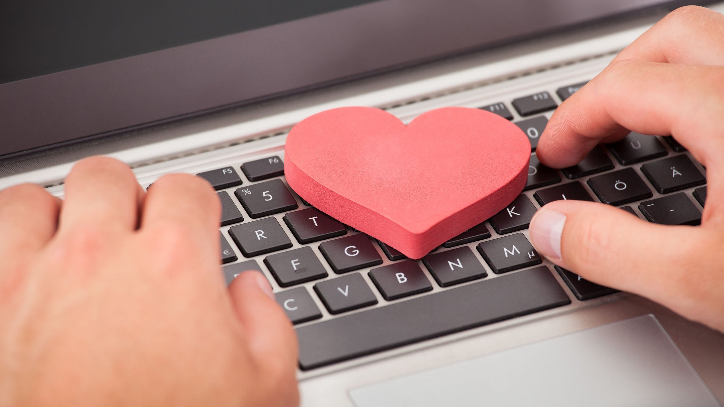 Pessoa escrevendo em um computador com um coração no meio