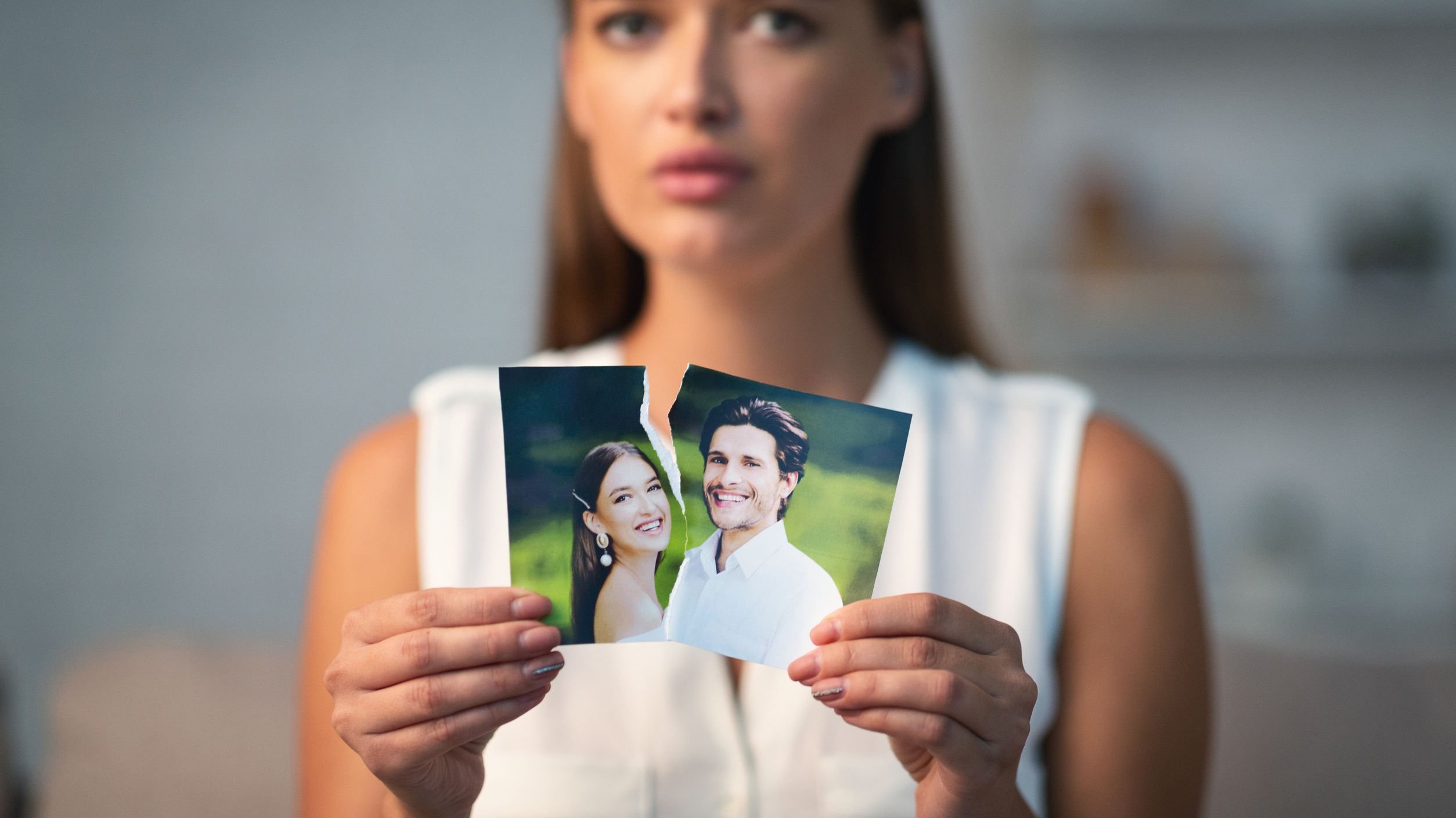 Mulher segurando uma foto rasgada dela com seu ex-namorado
