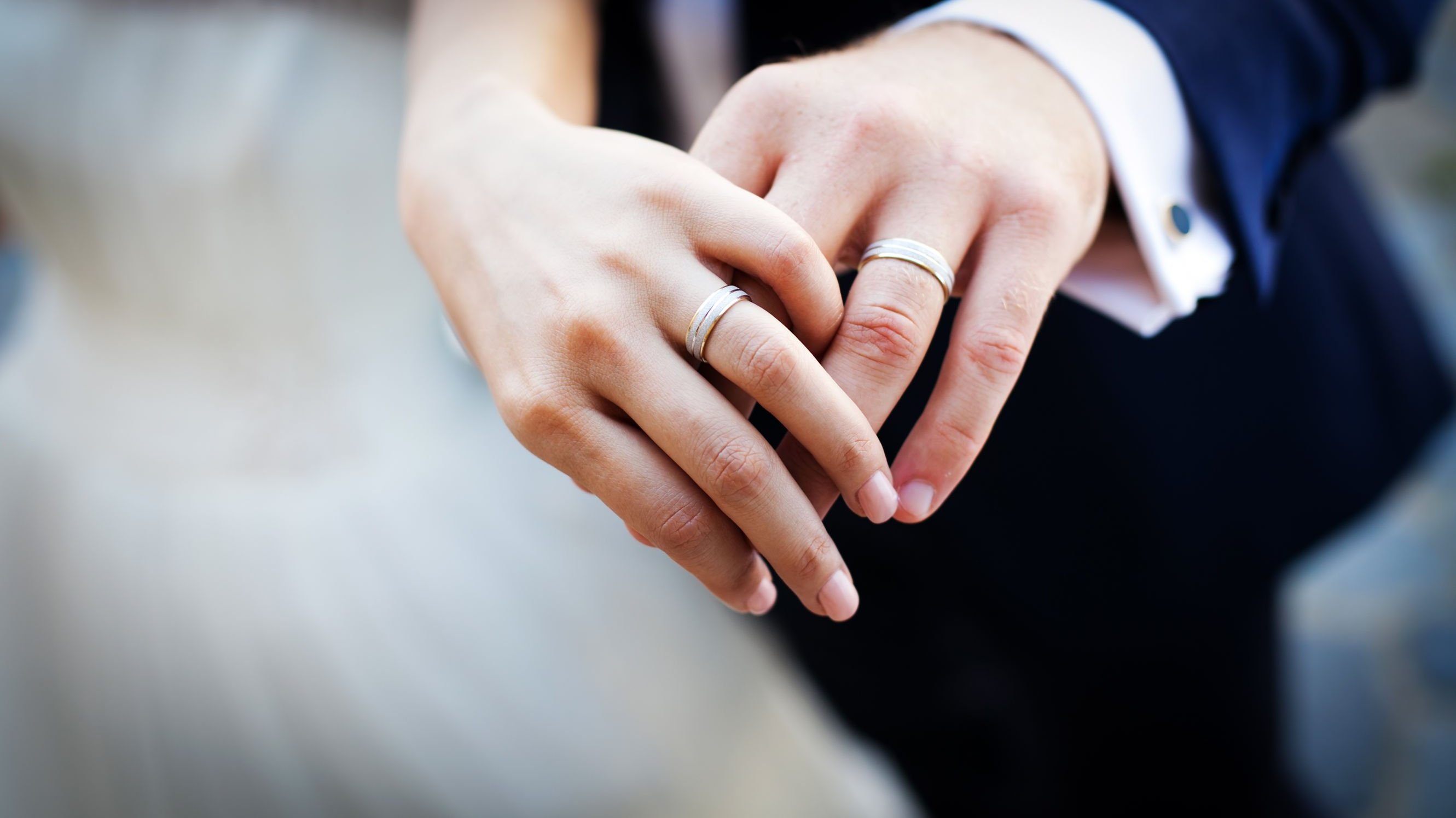 Homem e mulher mostrando suas alianças em seu casamento