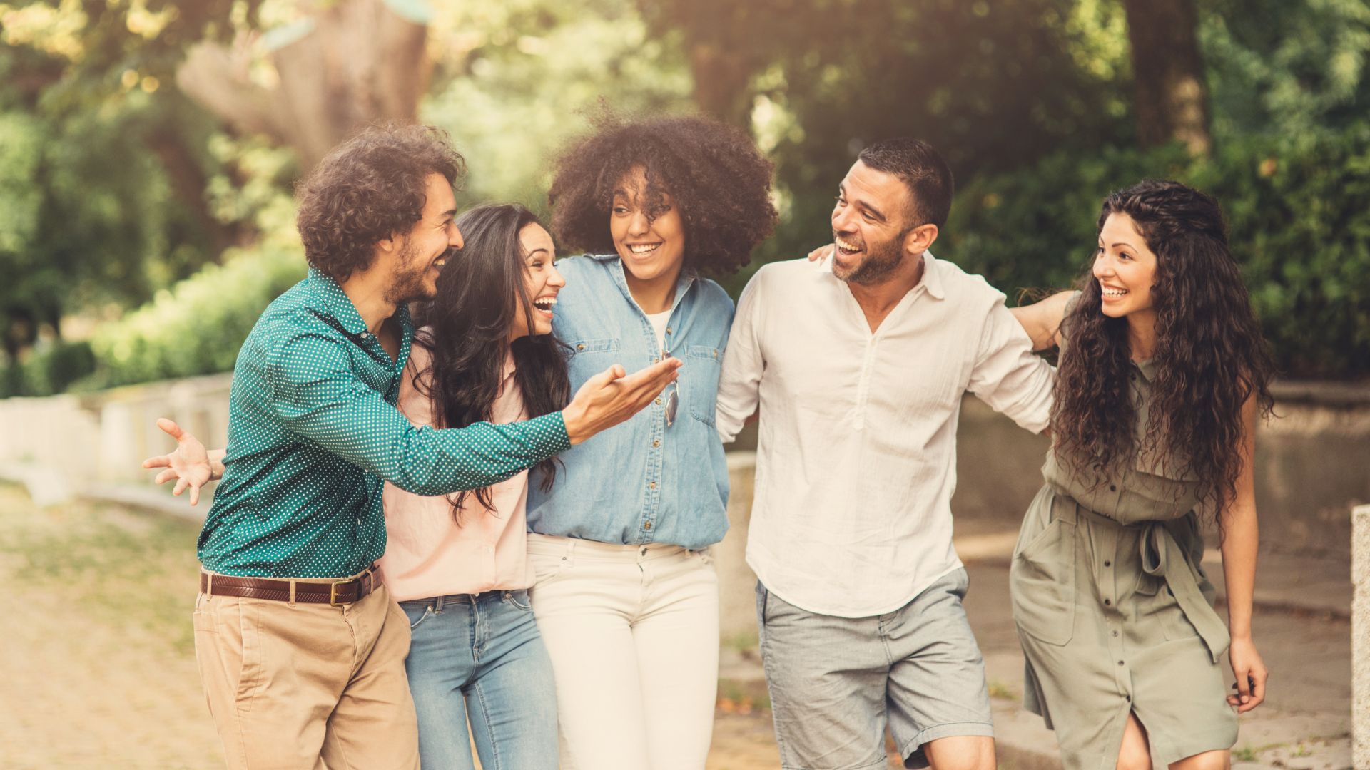 Imagem de cinco amigos abraçados, sorrindo e conversando.