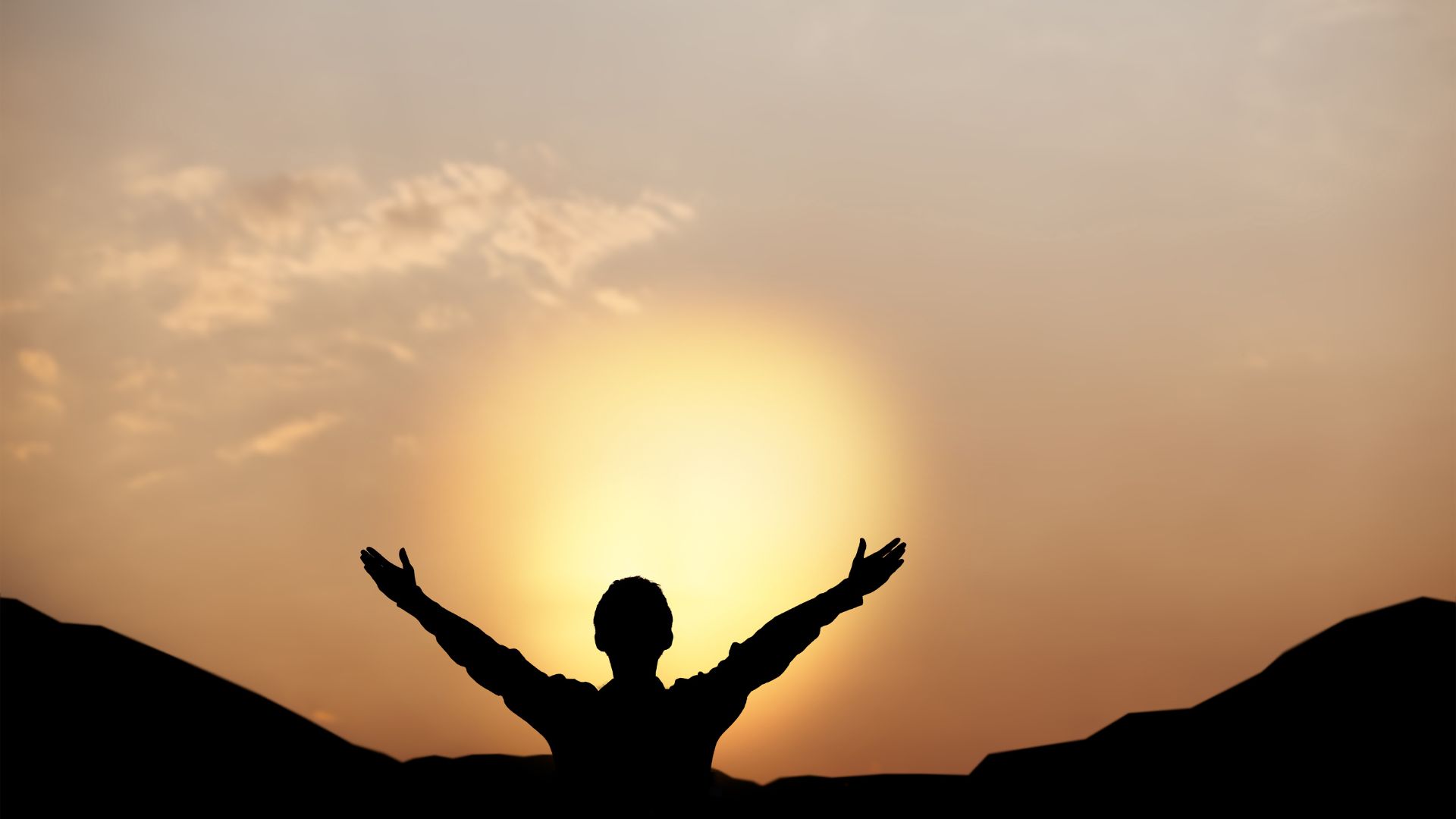 Imagem do pôr do sol e em destaque a silhueta de um homem olhando para o sol de braços abertos, conversando com Deus.