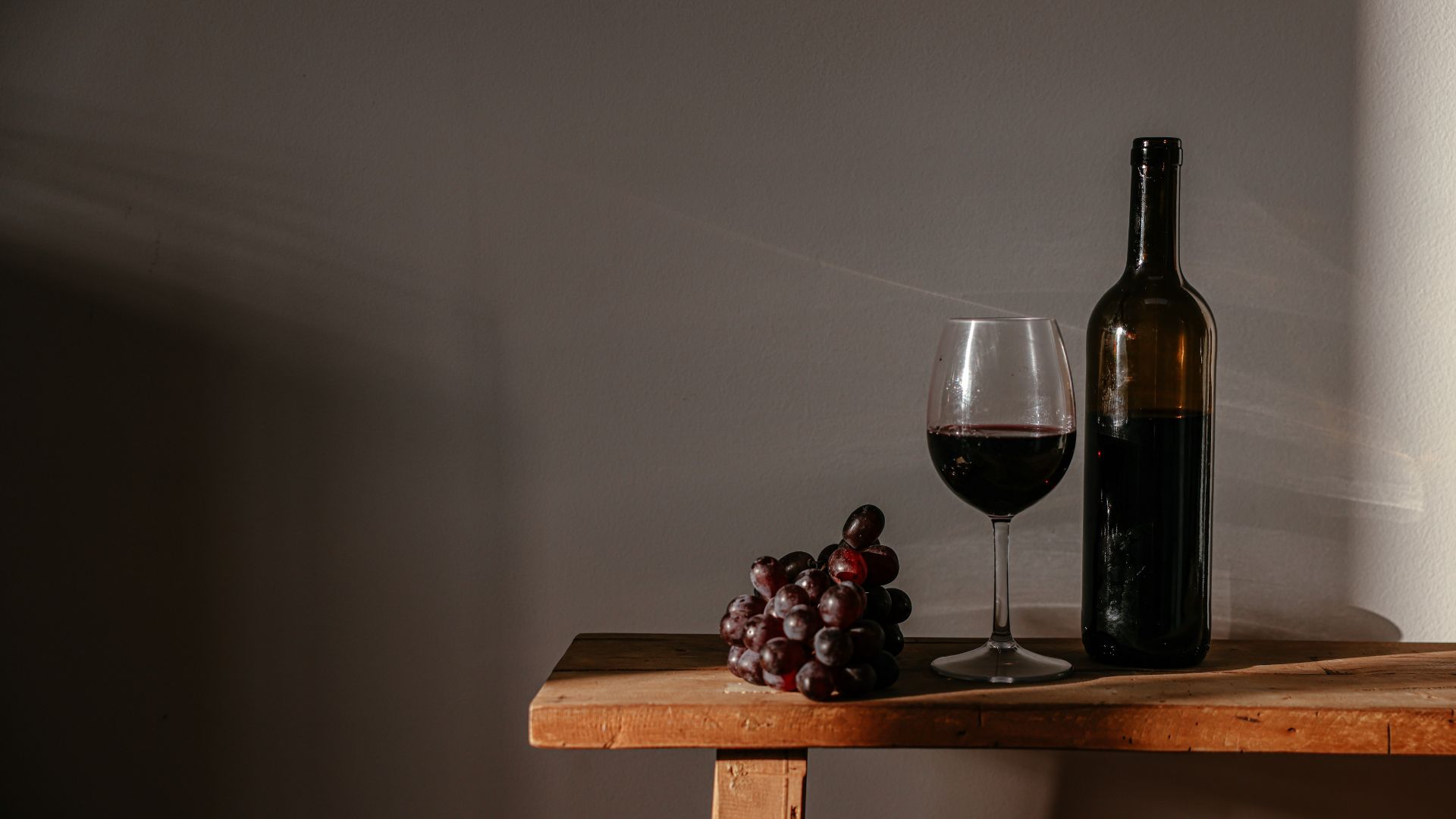 Cup of Couple de Pexels grátis para o Canva Pro Imagem de uma garrafa e uma taça de vinho em um banco de madeira