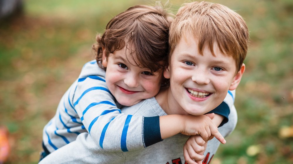 Dois irmãos juntos olhando e sorrindo para câmera