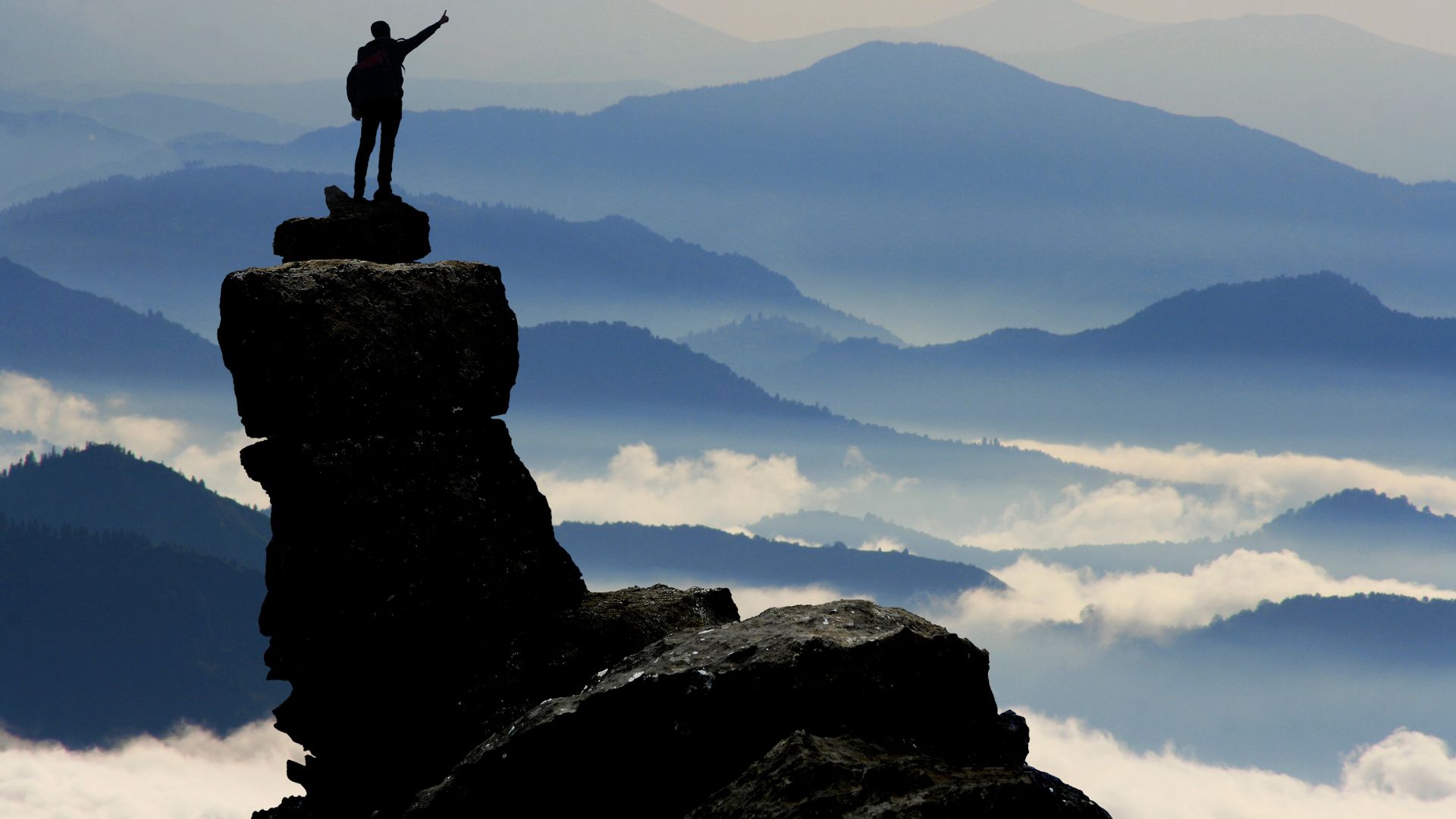 Imagem de um homem em pé sobre uma montanha, representando o sucesso de uma pessoa determinada.
