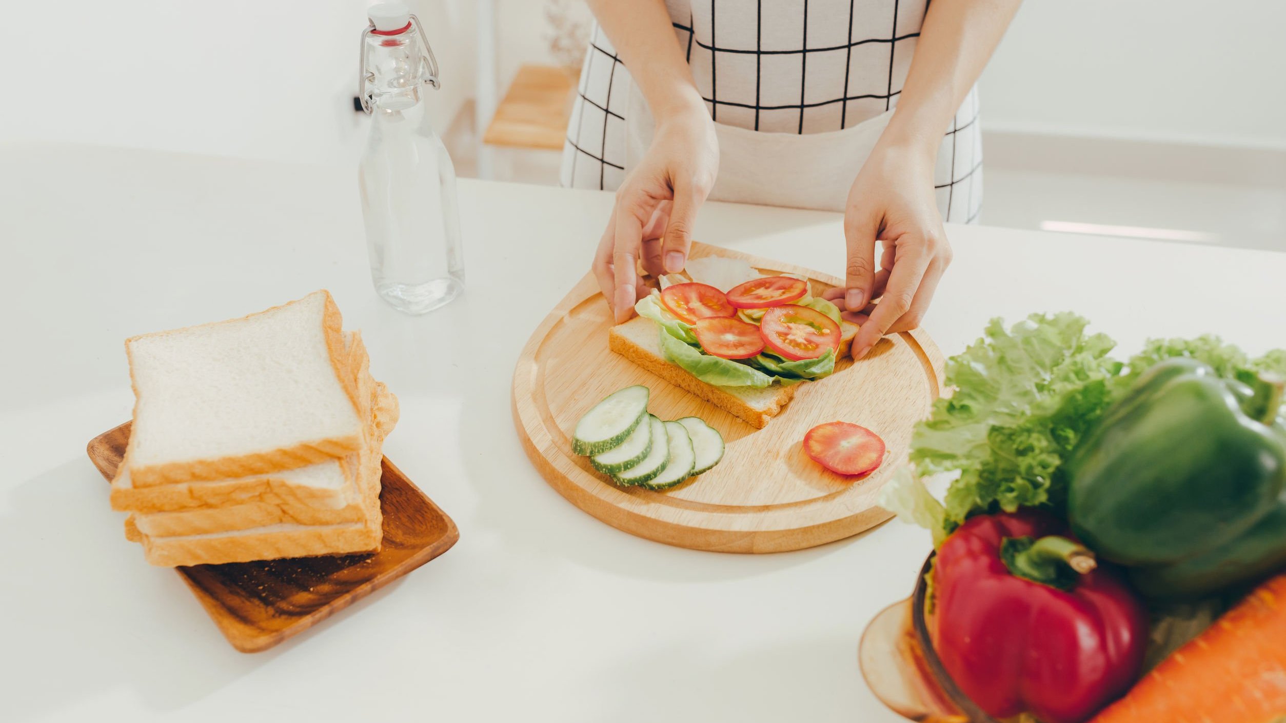 Mulher preparando um lanche com salada e tomate