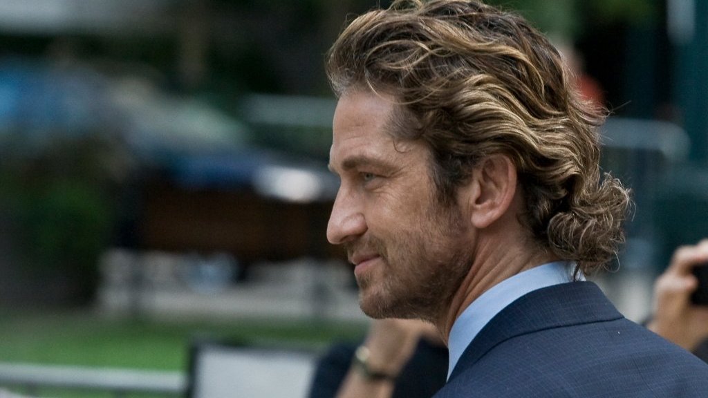 Gerard Butler de cabelo castanho claro, de perfil olhando para frente