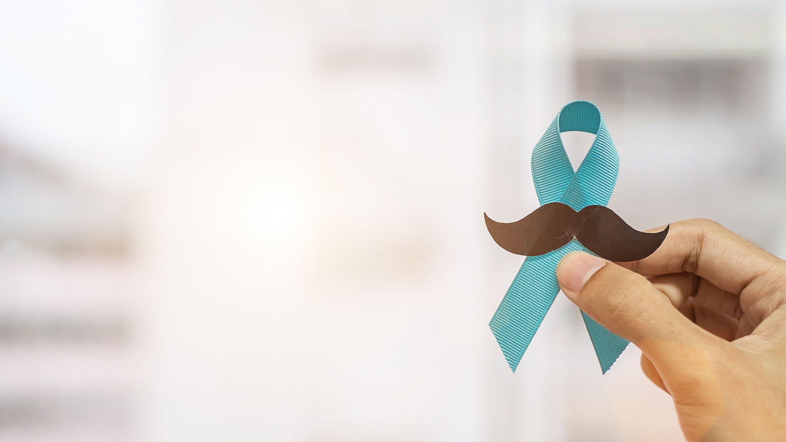 jopanuwatd / 123rf Mão masculina segurando fita azul e bigode falso.
