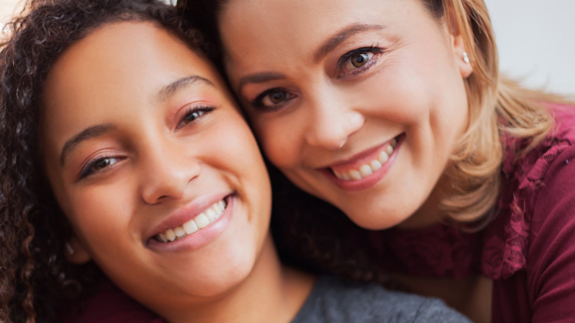 duas mulher abraçadas e sorrindo para a câmera