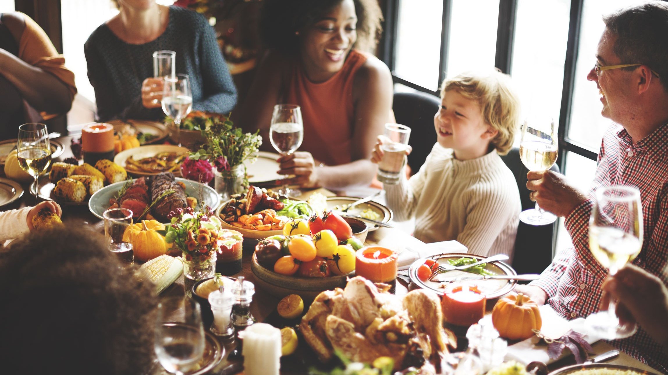 Família sentada ao redor de uma mesa durante jantar de Dia de Ação de Graças.