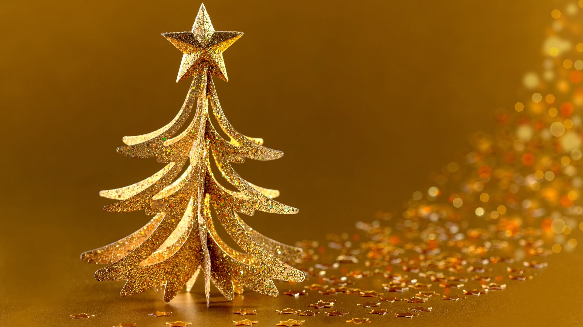 Imagem de fundo dourado e em destaque uma árvore de Natal pequena, também na cor dourada. Na ponta da árvore, temos uma estrela de 5 pontas.