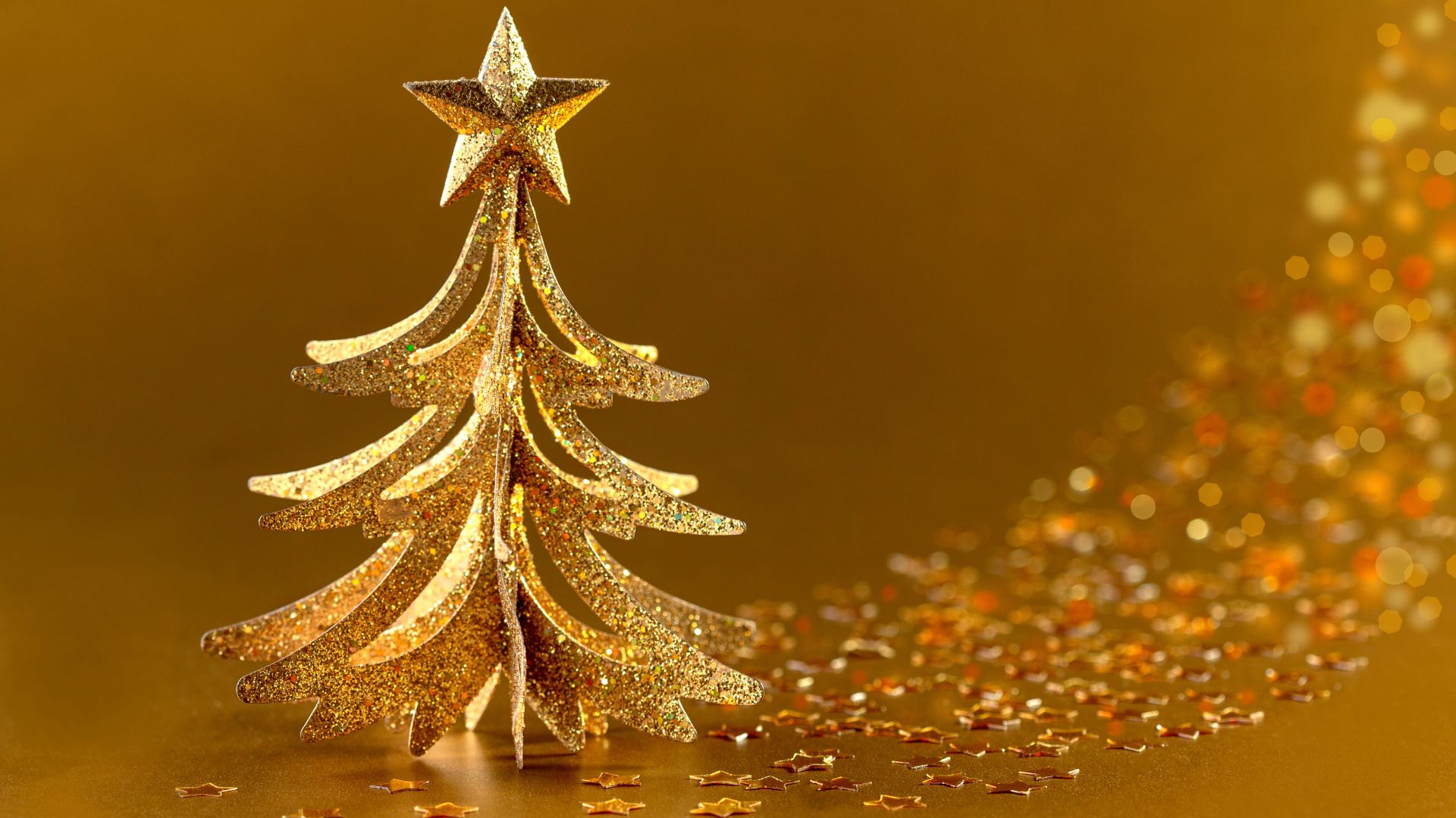 SMarina de Getty Images para o Canva Imagem de fundo dourado e em destaque uma árvore de Natal pequena, também na cor dourada. Na ponta da árvore, temos uma estrela de 5 pontas.