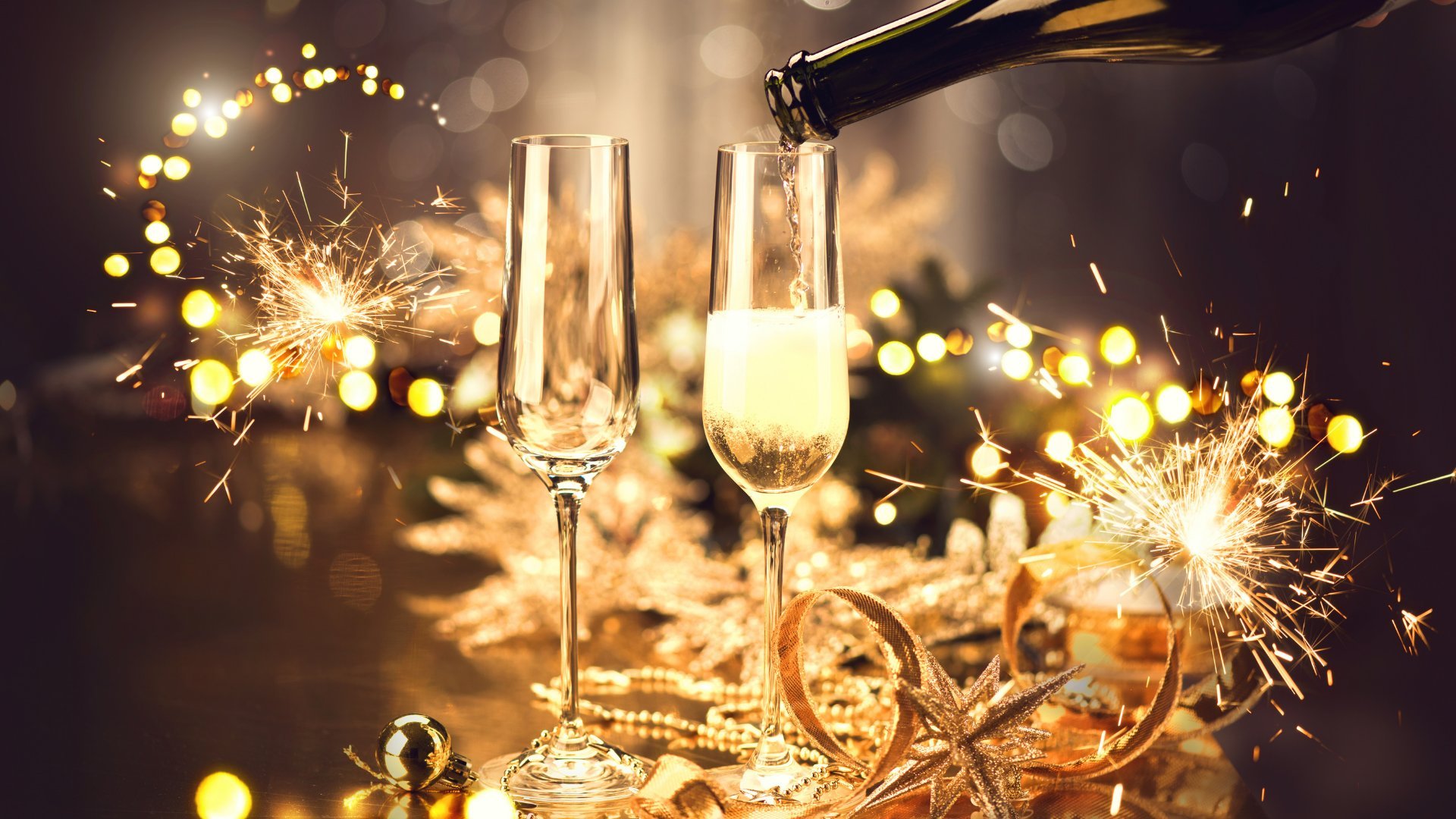 Imagem de celebração do ano novo com taças de champanhe e brilhos dourados