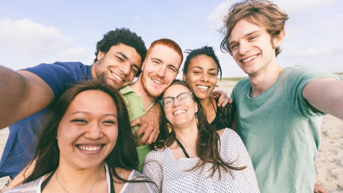 Grupo interracial de seis amigos posando para uma selfie.