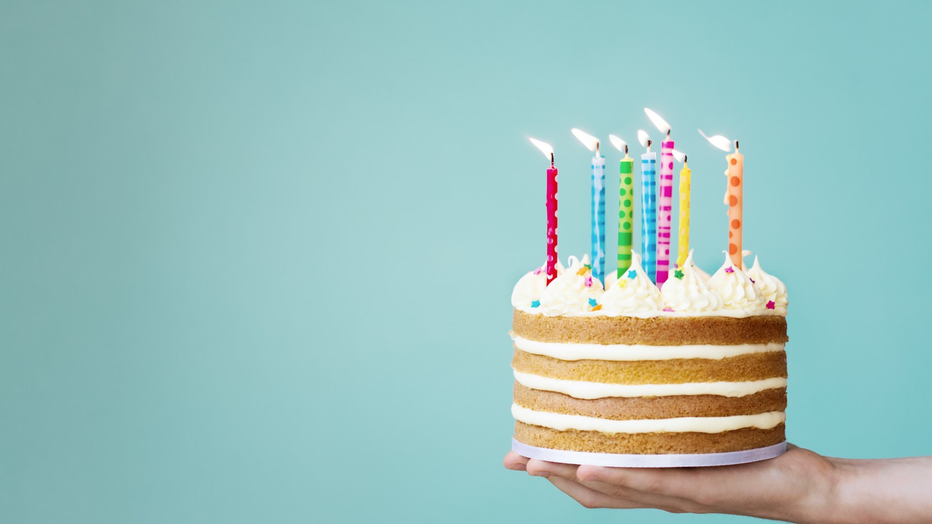 Pessoa segurando bolo de aniversário com velas acesas