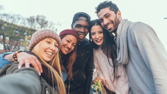 Cinco pessoas se abraçando enquanto tiram uma selfie