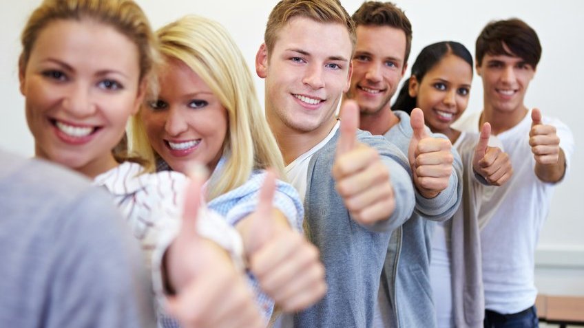 Jovens sorrindo com os polegares levantados.