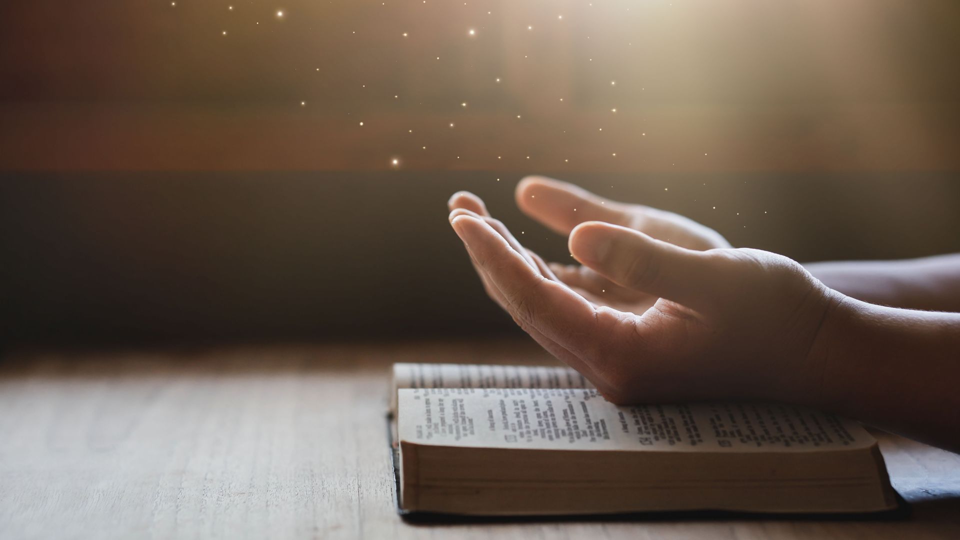 Imagem de uma pessoas com as mãos estendidas em cima da Bilblia e uma luz vindo sobre as mãos